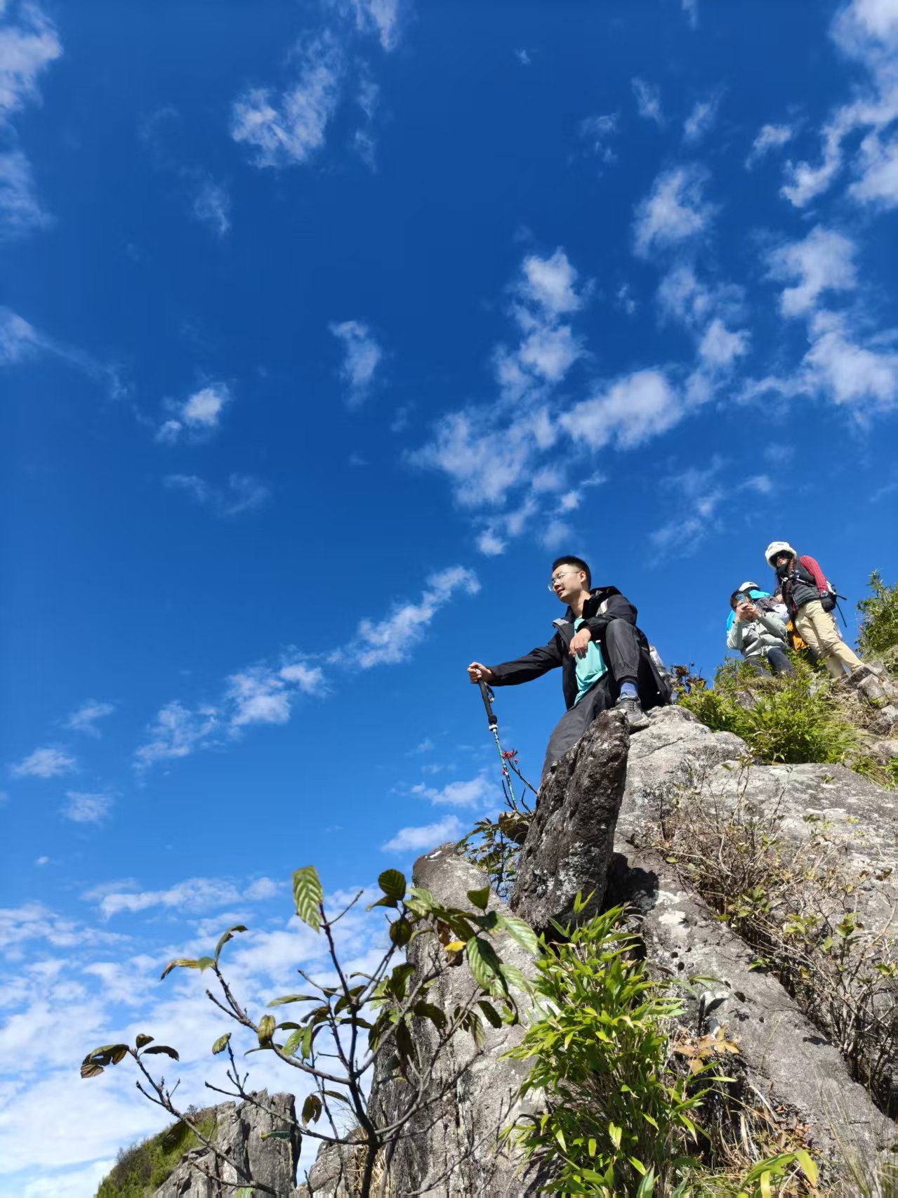 唐玮在清凉峰山顶的岩石旁,身后是蓝天与同行者